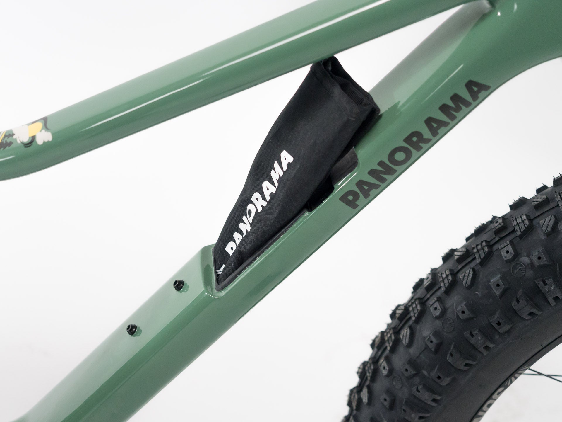 Close-up of green Panorama Cycles bicycle frame showing integrated frame bag and knobby fat tire on white background
